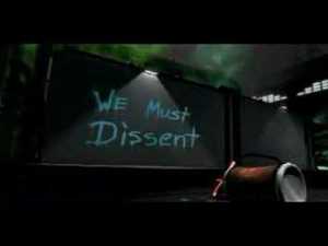 A video still showing a concrete wall, at night, with "We Must Dissent" spraypainted on it blue paint, the spray can sitting on its side in the foreground.